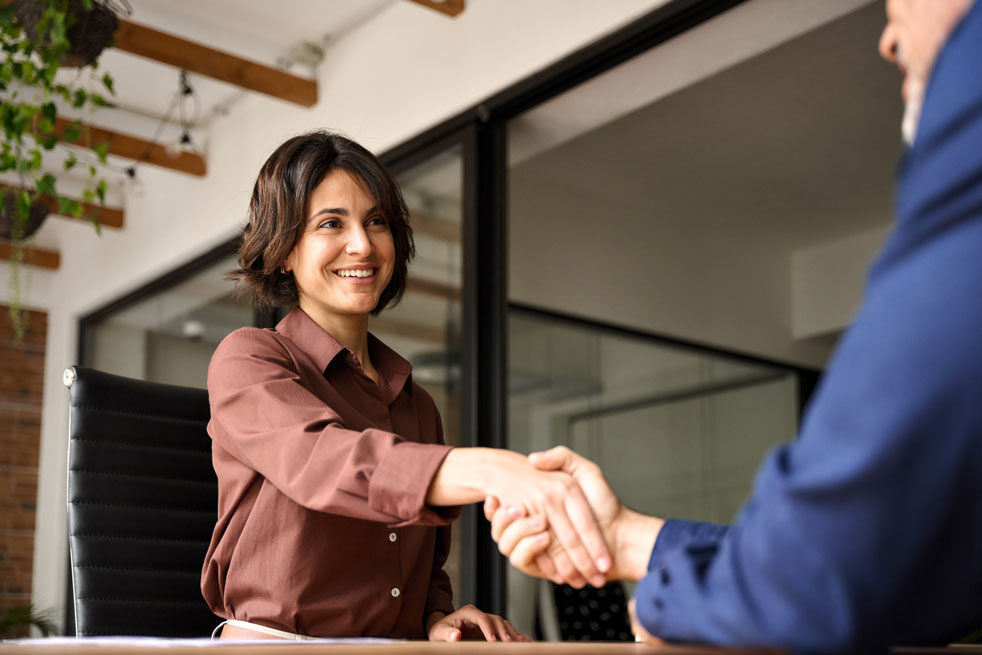 Happy young business woman bank manager handshaking client at meeting. Smiling female hr hiring recruit at job interview, insurance agent, lawyer making contract deal at work with business handshake.